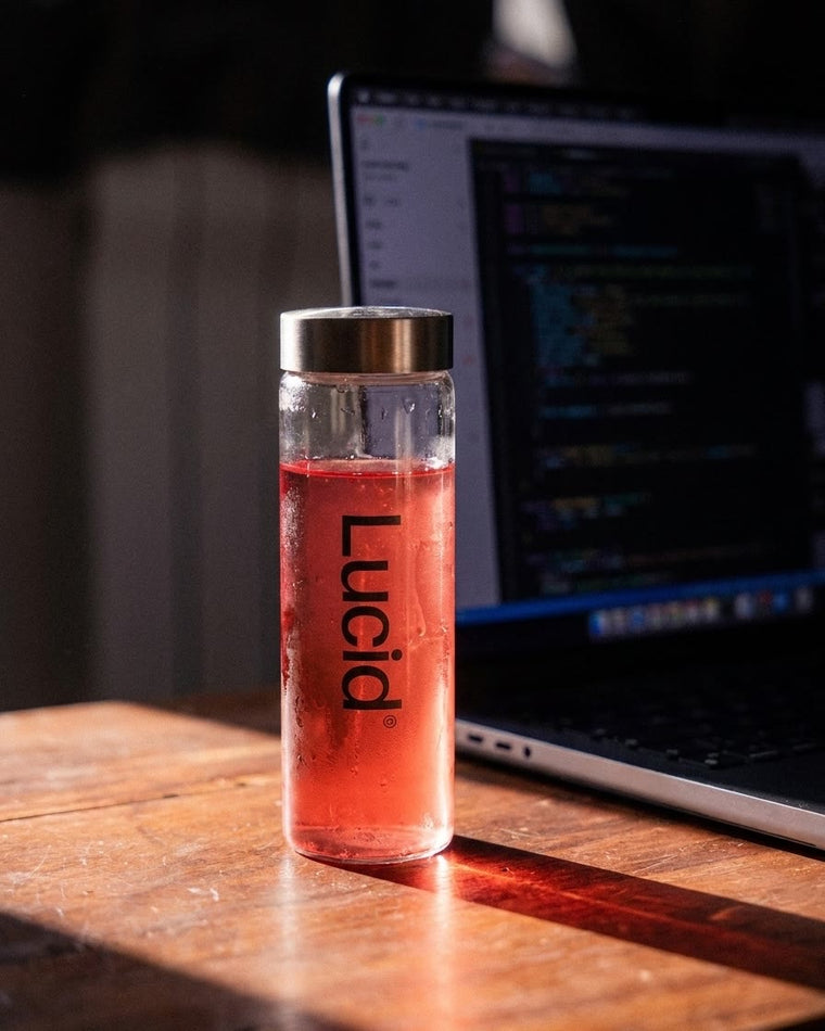 Une bouteille Lucid posée sur un bureau, à côté d'un ordinateur ouvert